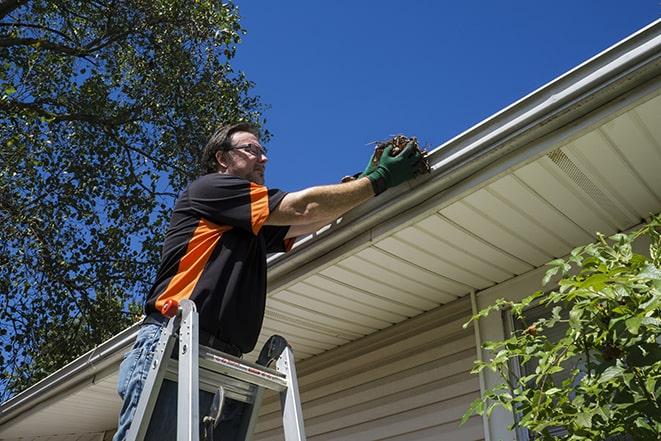 the process of repairing a broken gutter on a building in Boron